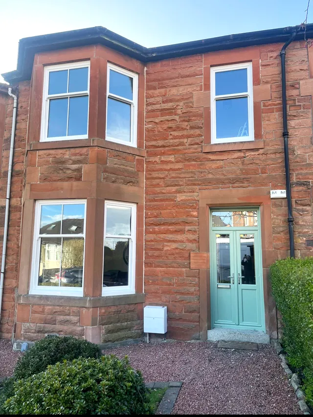 Red sandstone villa with traditional sash and case windows and a green door